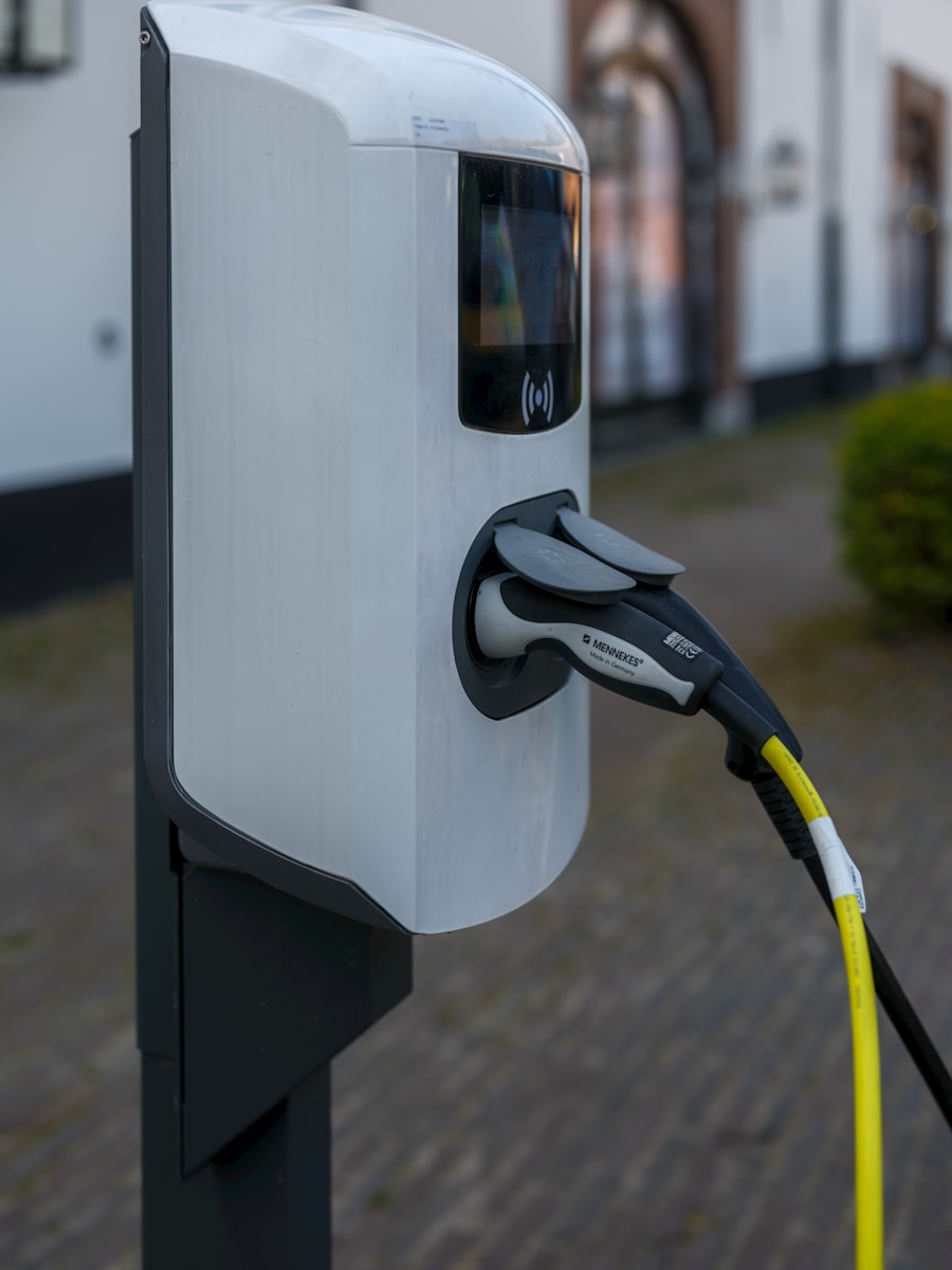 Sähköauton latausasema oulussa. Sähkömies asentaa kuormanhallintaa latausasemaan, jotta sulake ei pala.